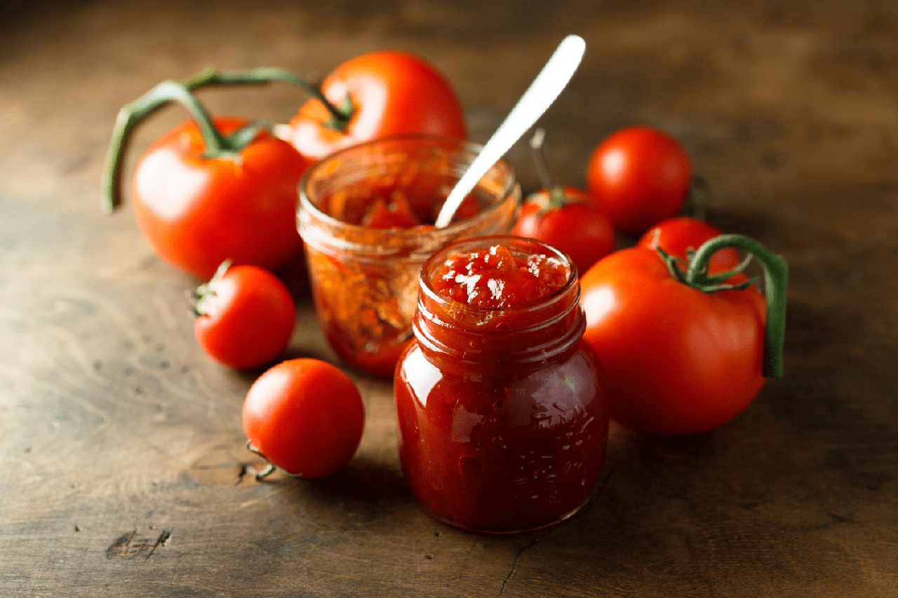 il chutney di scarti di pomodoro in un barattolo e dei pomodorini freschi