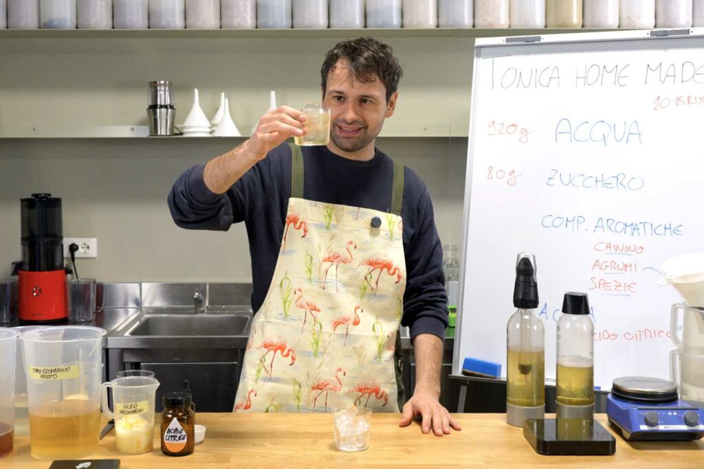 Dietro al banco bar del laboratorrio, Giovanni Ceccarelli mostra un bicchiere con dentro una acqua tonica home made appena preparata.